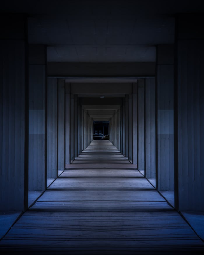 A dramatic view of a modern hallway with symmetrical columns creating an infinite perspective.